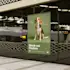 Block-out poster displayed on a black wall at a train station, featuring a beagle dog on a green background with the text
