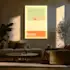 Illuminated poster displayed on a wall in a cozy, modern living room with warm lighting, featuring a minimalist design and the word