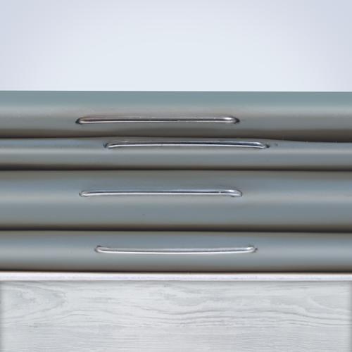 A stack of four grey stapled booklets on a wooden table showcasing the staple binding.