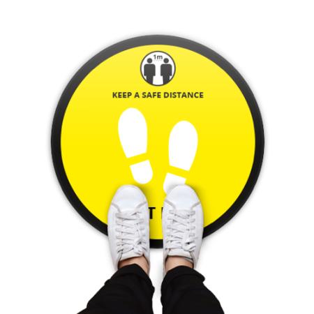 Round floor sticker with a yellow background and the text 