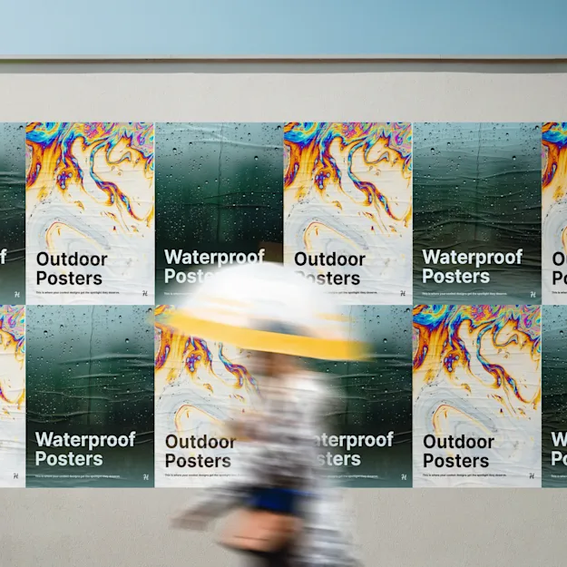 Wall display of alternating waterproof and outdoor posters featuring raindrop and abstract oil-pattern designs, with a person walking past with an umbrella
